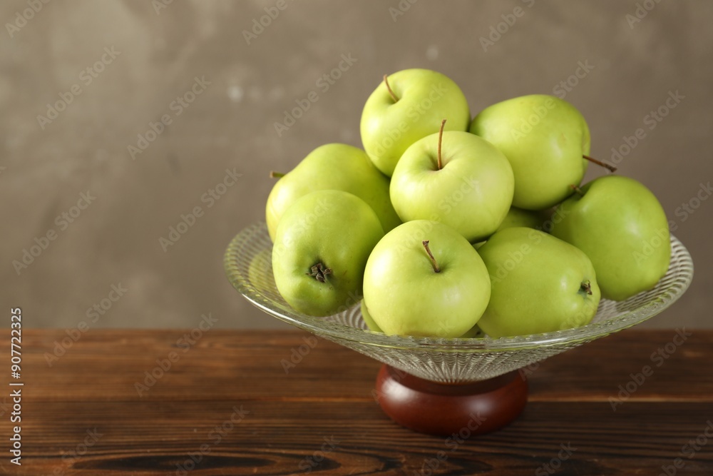 Glass vase with fresh green apples on wooden table against gray background, closeup. Space for text Glass vase with fresh green apples on wooden table against gray background, closeup. Space for text