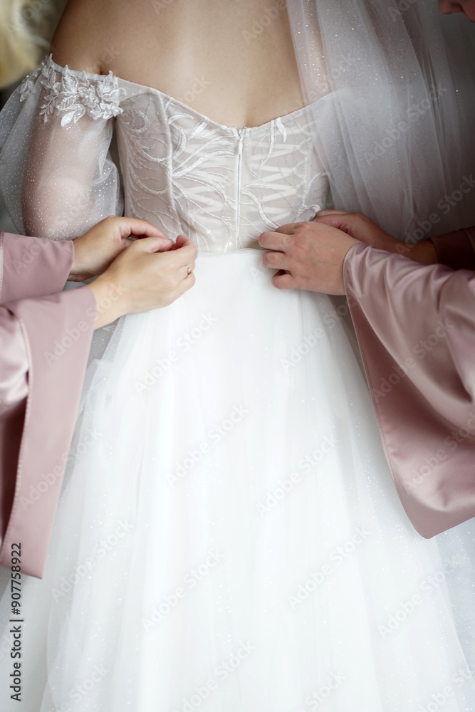 The bride's friends help to put on the wedding dress. Morning of the bride. Preparation for the wedding. The bride's friends help to put on the wedding dress. Morning of the bride. Preparation for the wedding.