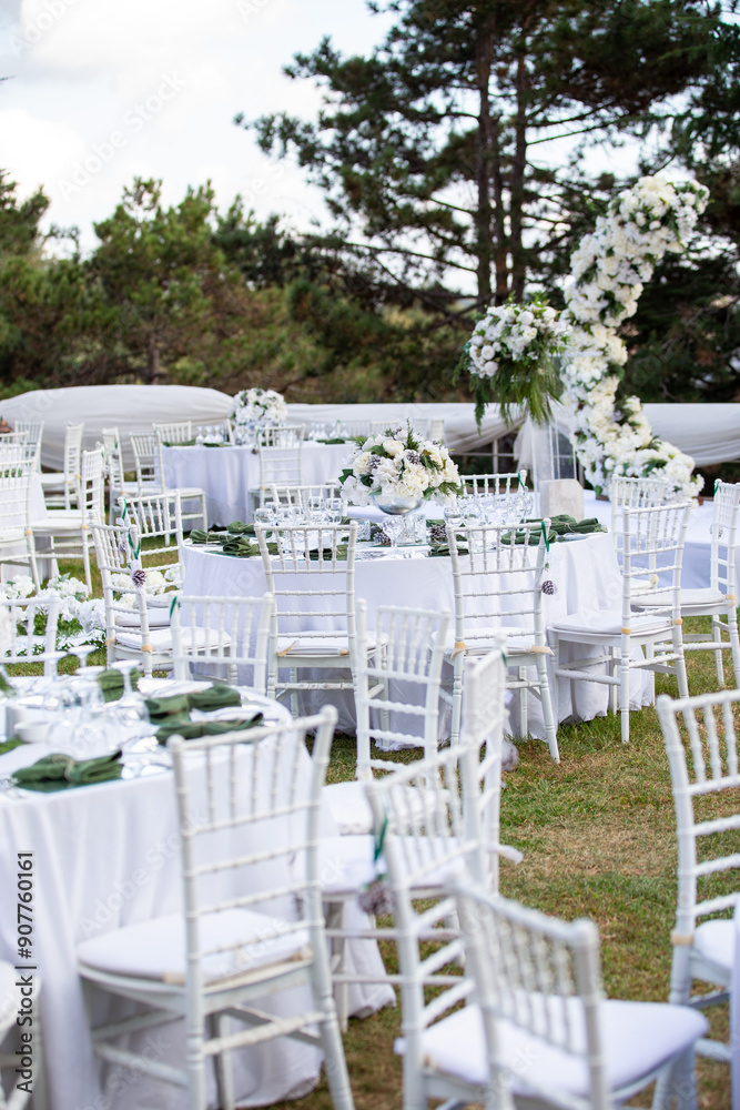 Romantic outdoor wedding reception with round tables, white linens, and floral centerpieces, surrounded by lush greenery Romantic outdoor wedding reception with round tables, white linens, and floral centerpieces, surrounded by lush greenery