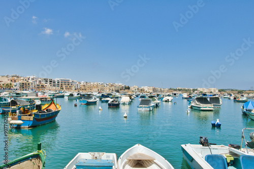 BIRZEBBUGA, MALTA - JUNE 28, 2023: the Colorful small fishing boats moored with buoys in St George's Bay, in Birzebbuga, Malta. This was on a sunny afternoon.