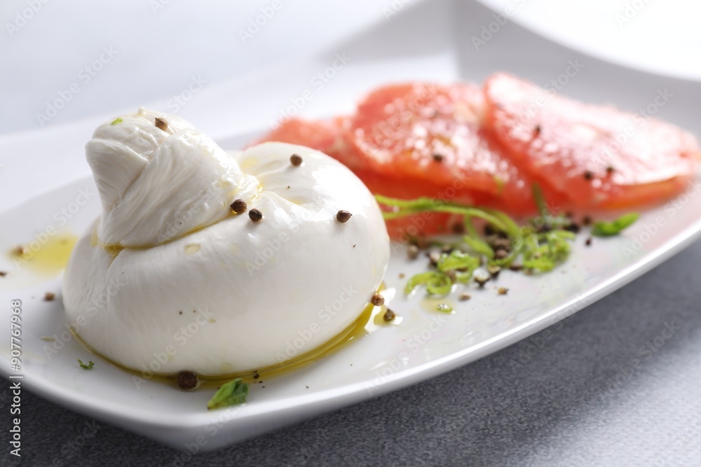 Delicious burrata cheese, grapefruit and spices on light grey table, closeup Delicious burrata cheese, grapefruit and spices on light grey table, closeup