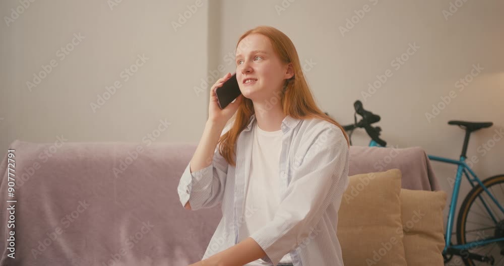 Red-haired woman picks up smartphone with warm smile Red-haired woman picks up smartphone with warm smile