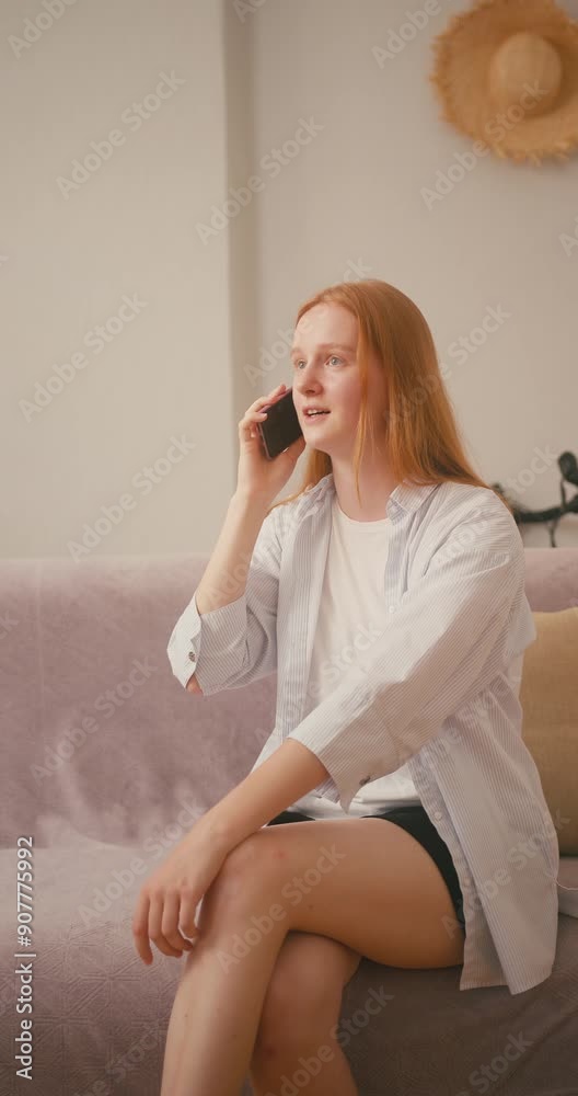 Red-haired woman picks up smartphone with warm smile Red-haired woman picks up smartphone with warm smile