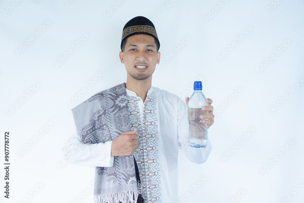Moslem Asian man smiling happy while showing drinking plastic bottle Moslem Asian man smiling happy while showing drinking plastic bottle