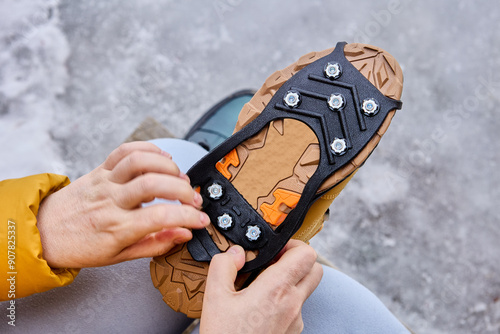 Cuadro en lienzo Over shoe rubber pad with spikes, anti slip ice cleats, woman installs non-slip pad on trekking shoes