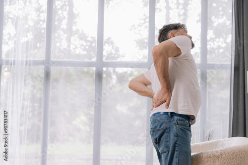Free Download Rear view of senior man suffering from back pain on sofa at home, copy space for your advertising - GFXLoad