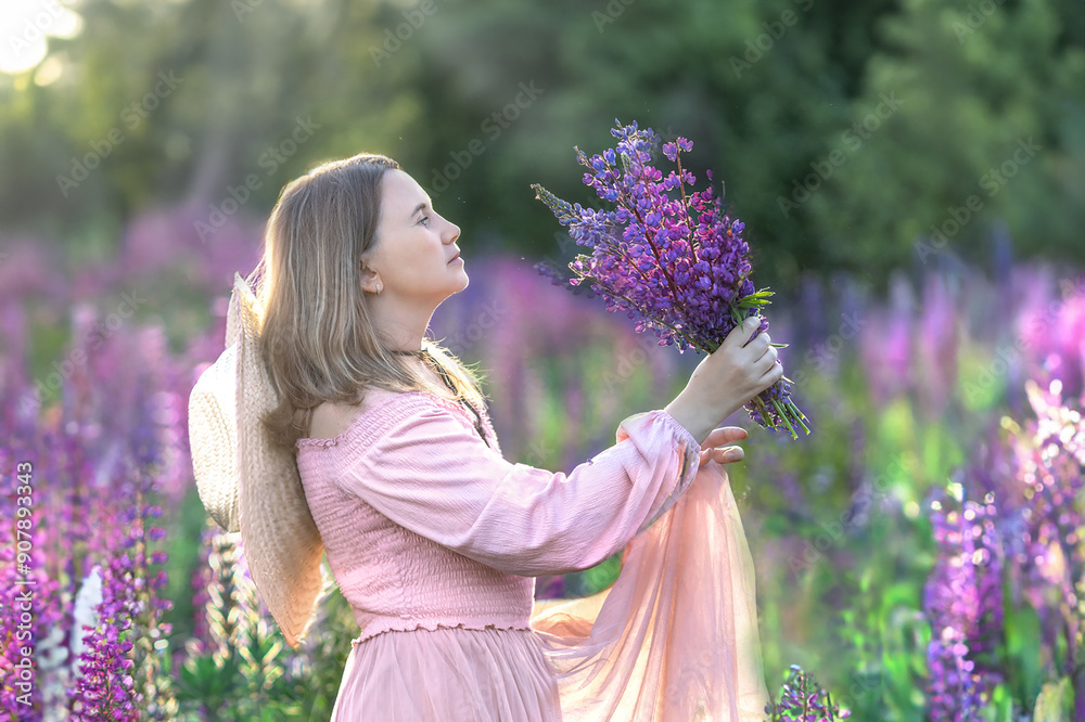 Beautiful girl with londy hair in the summer in a field of blooming purple lupine flowers with a bouquet in her hands Beautiful girl with londy hair in the summer in a field of blooming purple lupine flowers with a bouquet in her hands