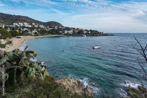 Beautiful view on the Rosas beach with a boat in the middle of the bay with mountains on the background. Spain