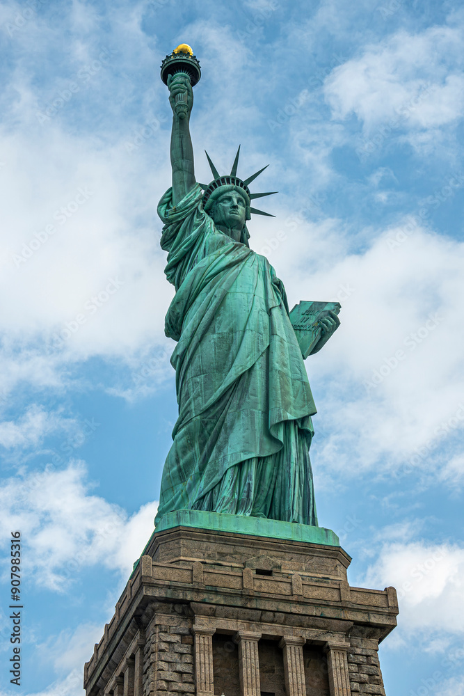 Fototapeta premium New York, NY, USA - August 4, 2023: Miss Liberty statue closeup, against blue cloudscape