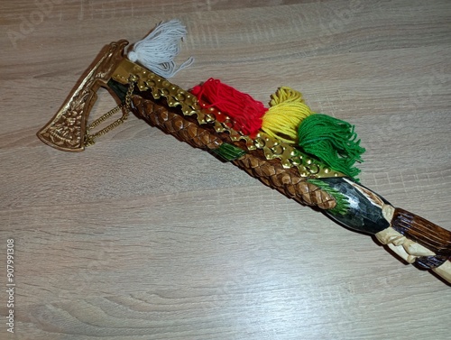 A yellow metal traditional mountain ax lies on a wooden surface. Souvenir ax with carvings and bonbons photo