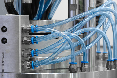 Close-up of precise industrial equipment with pneumatic components: orange plastic tubes with connectors. Industrial concept background.