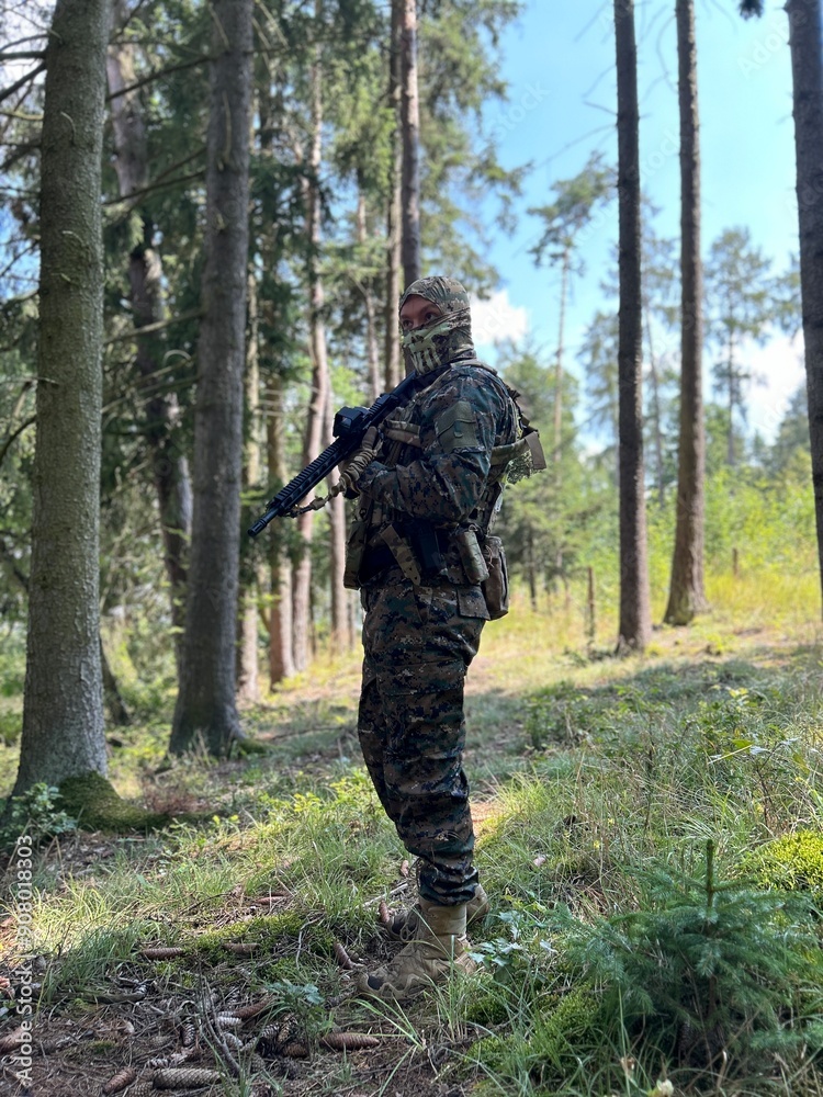 A soldier aiming a rifle. A soldier with a rifle in his hand standing in the forest. Dressed in camouflage. A soldier aiming a rifle. A soldier with a rifle in his hand standing in the forest. Dressed in camouflage.