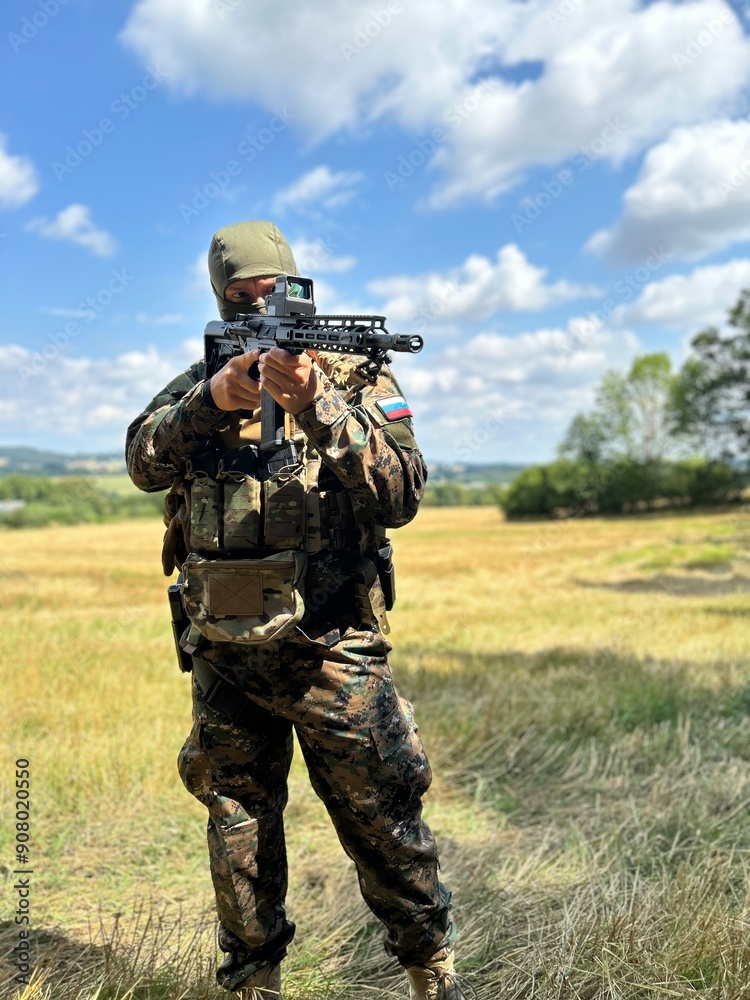 Fototapeta premium A Russian soldier guards the captured area. A soldier in camouflage with a rifle in his hand. Tracks enemy movement.