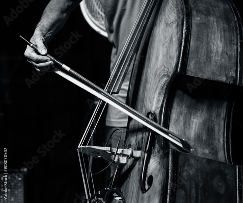 Canvas Print A black and white photo featuring the detail of a bow playing an upright bass, with a focus on the jazz bassist's hand