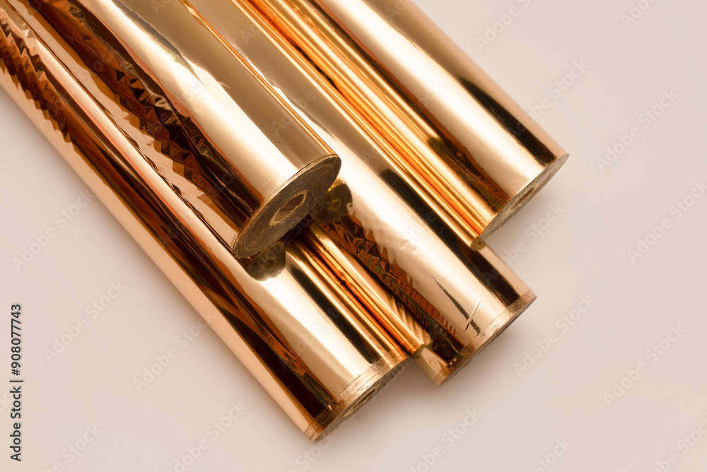 Rolls of gold foil on a beige background, metallized gold foil for embossing decorative elements through cliches and thermopresses, text on book covers, notebooks, business cards Rolls of gold foil on a beige background, metallized gold foil for embossing decorative elements through cliches and thermopresses, text on book covers, notebooks, business cards