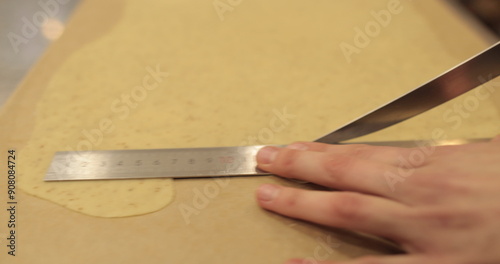 Preparation of dough for tarts. The chef measures and cuts the dough with his hands on the kitchen table. Female hands are preparing dough on a metal table