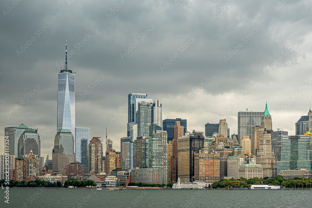 Obraz premium New York, NY, USA - August 4, 2023: Manhattan skyline N of Battery Park under gray menacing cloudscape, seen from the SW