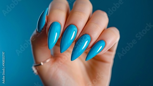 A woman's hand holding a blue manicure with a ring on it photo