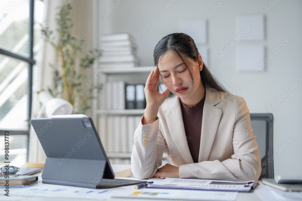 Businesswoman feeling stressed and having a headache while working on a laptop in the office Businesswoman feeling stressed and having a headache while working on a laptop in the office