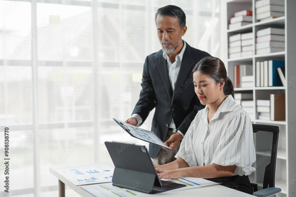 Asian manager showing document to young accountant using digital tablet for financial analysis