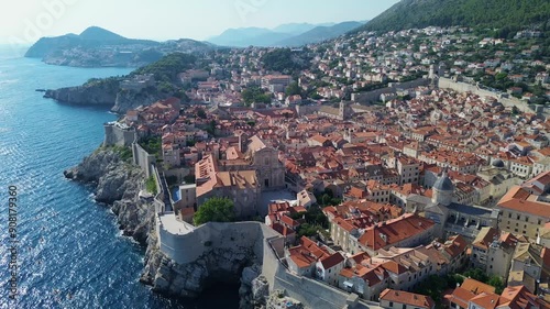 Aerial drone film of the historic, ancient walled city of Dubrovnik in Croatia on the Adriatic Sea. Summer colourful city view with defence wall, narrow illuminated streets tiled roofs and fort church photo