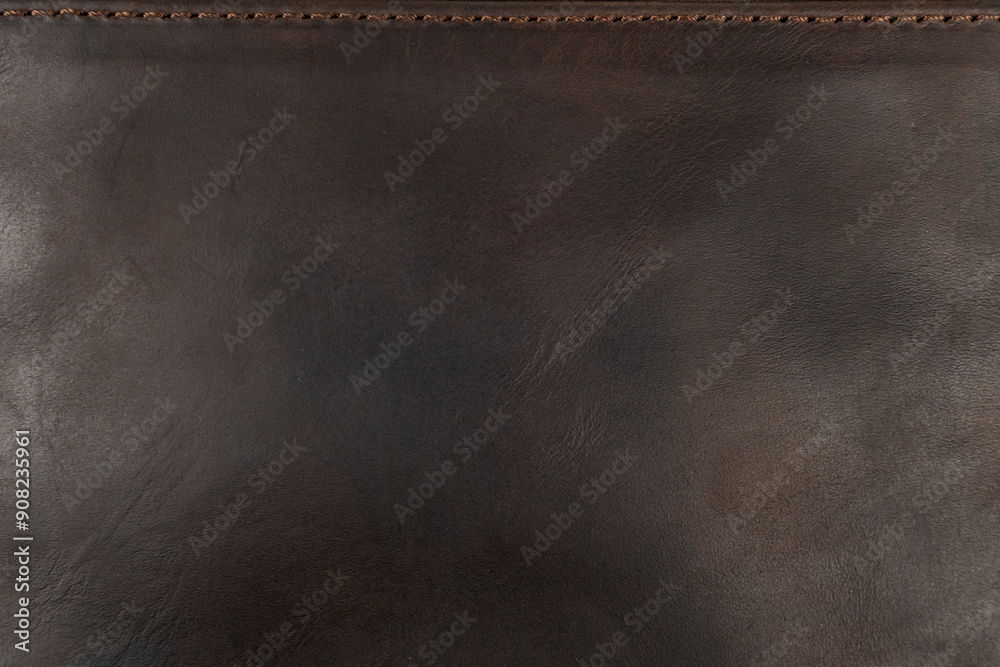 Dark brown leather surface with stitching on the top and copyspace. Dark brown leather surface with stitching on the top and copyspace.