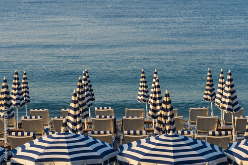 Fototapeta Naklejka Na Ścianę i Meble -  Umbrellas and sunbeds on the beach in Nice in the south of France on a summer morning.