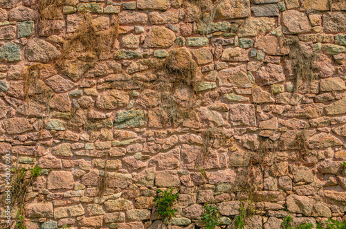 stone wall, texture, Medieval natural stone wall, pink granite, French masonry stone wall, background for photo.,moss, plants on the stone wall