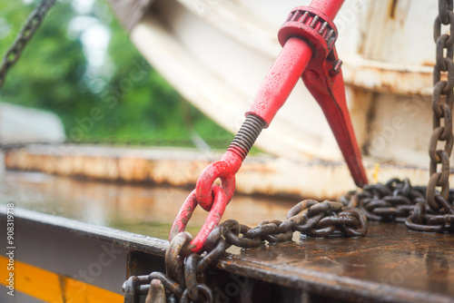 Steel chain and hook securing anchor, using to secure heavy object that transported on the trailer truck. Industrial safety equipment, close-up at the object.