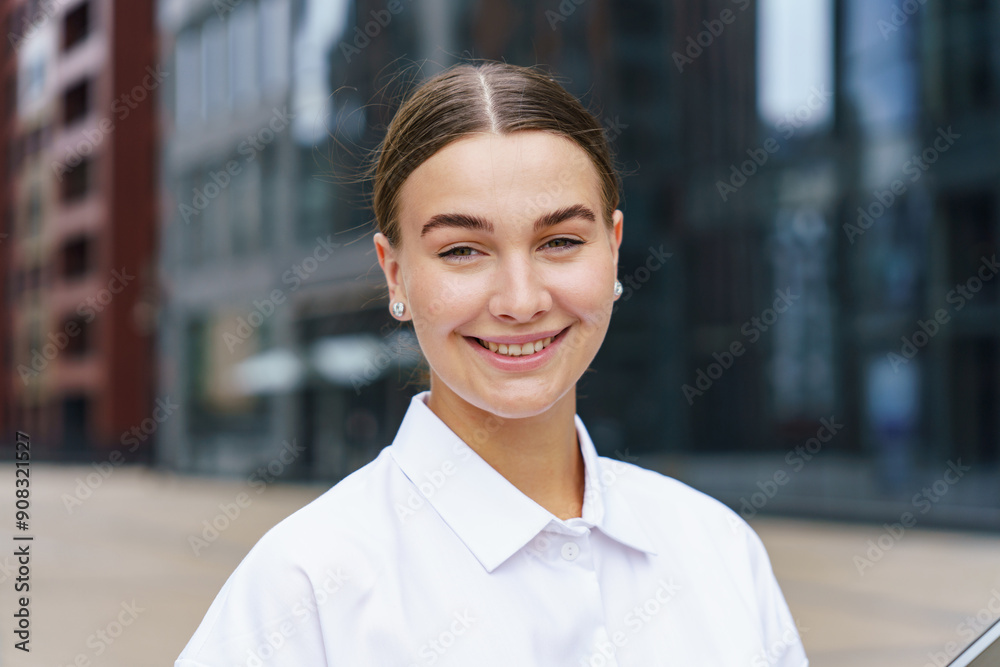 Smiling woman in a white shirt standing outdoors with a modern urban background. Smiling woman in a white shirt standing outdoors with a modern urban background.