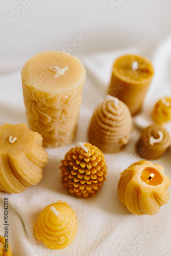 Handmade candles from natural beeswax in the shape of flowers, bears on a white background. Hobby. Handmade present. Gift. Artistic photo of beekeeping products in white room. Mockup. 