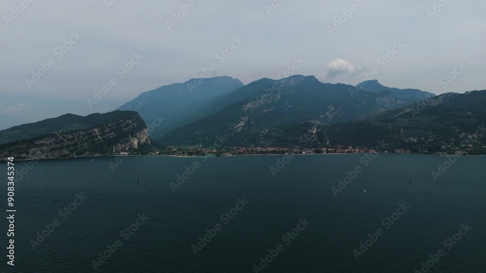 Aerial shot of Riva del Garda. Famous port on Lake Garda with boats sailing across the surface of the large Italian lake. Peace, summer activities, blue water and mountains. Stock footage 4k 50fps. Aerial shot of Riva del Garda. Famous port on Lake Garda with boats sailing across the surface of the large Italian lake. Peace, summer activities, blue water and mountains. Stock footage 4k 50fps.