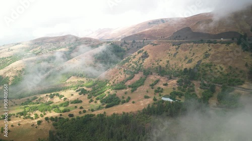 Aerial of low clouds through dry grassy brown hill by White Bird Idaho in summer photo