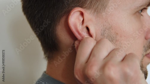 Caucasian man massaging his right ear with his fingers close up. Impact on nerve endings of auricle and earlobe. Nervous movements of anxious person to calm him down.