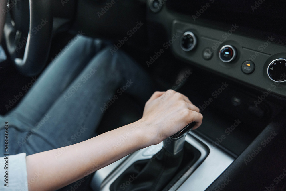 Woman's hands gripping the steering wheel of a car with the gear stick prominently in the center console, emphasizing driving focus and interior vehicle details Woman's hands gripping the steering wheel of a car with the gear stick prominently in the center console, emphasizing driving focus and interior vehicle details