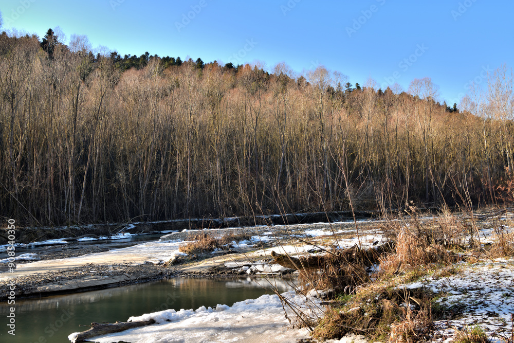Flowing river in winter with ice banks and snow in the vicinity