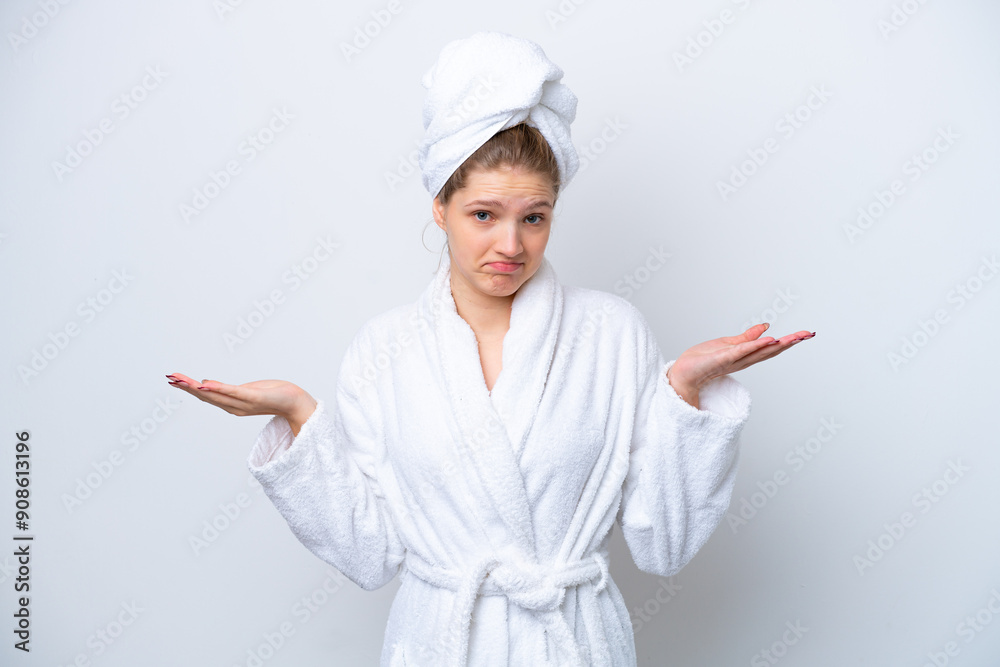 Teenager Russian girl in a bathrobe isolated on white background having doubts while raising hands Teenager Russian girl in a bathrobe isolated on white background having doubts while raising hands