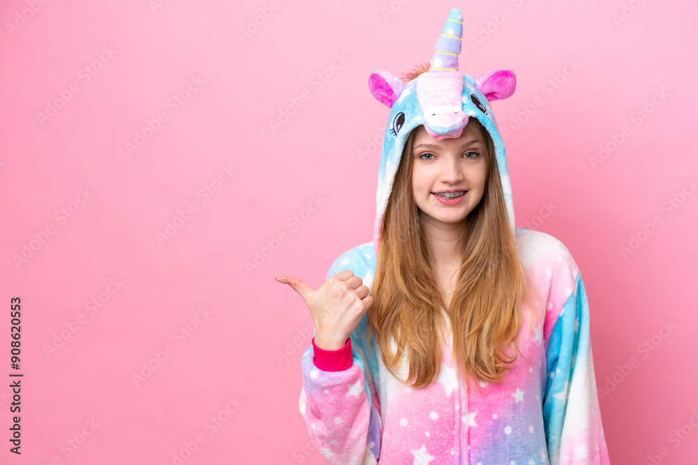 Teenager Russian girl with unicorn pajamas isolated on pink background pointing to the side to present a product Teenager Russian girl with unicorn pajamas isolated on pink background pointing to the side to present a product