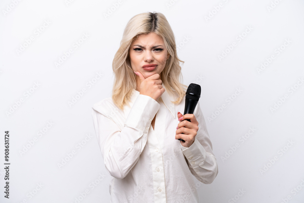 Young singer woman picking up a microphone isolated on white background thinking Young singer woman picking up a microphone isolated on white background thinking