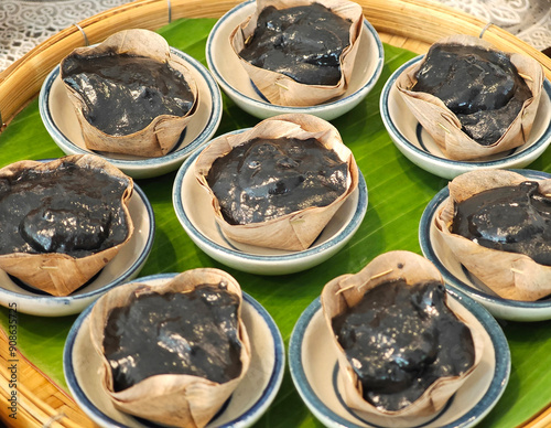 Charcoal pandanus pudding with coconut cream on dried banana leaf. photo