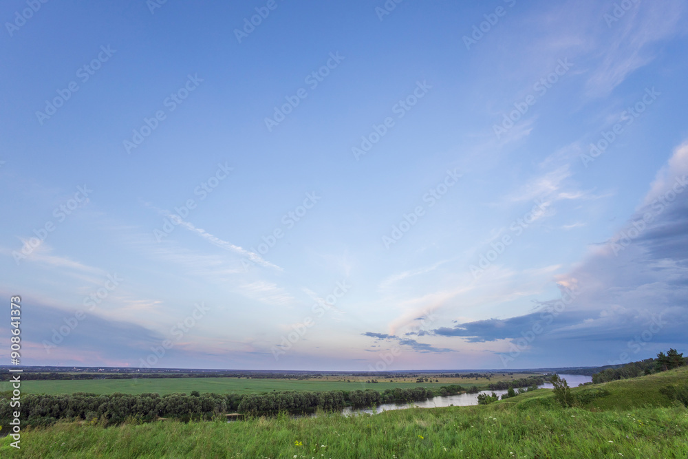 A tranquil view of a meandering river snaking through verdant fields. The sky above is a canvas of soft, white clouds against a backdrop of azure blue, creating a picturesque scene. A tranquil view of a meandering river snaking through verdant fields. The sky above is a canvas of soft, white clouds against a backdrop of azure blue, creating a picturesque scene.