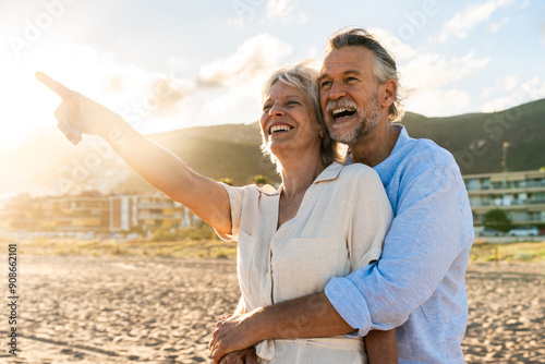 Beautiful happy senior couple dating at the seaside during summertime - Mature married couple in love bonding outdoors at the beach, concepts about elderly lifestyle, relationship and quality of life photo