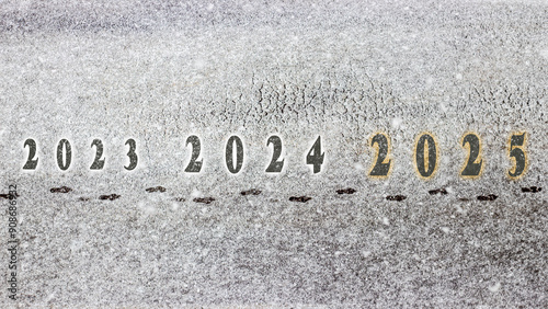 Footsteps in the snow marking the transition from 2023 to 2024, and finally to 2025, symbolizing progress and the journey into the new year, set against a snowy background..New year 2025 concept.