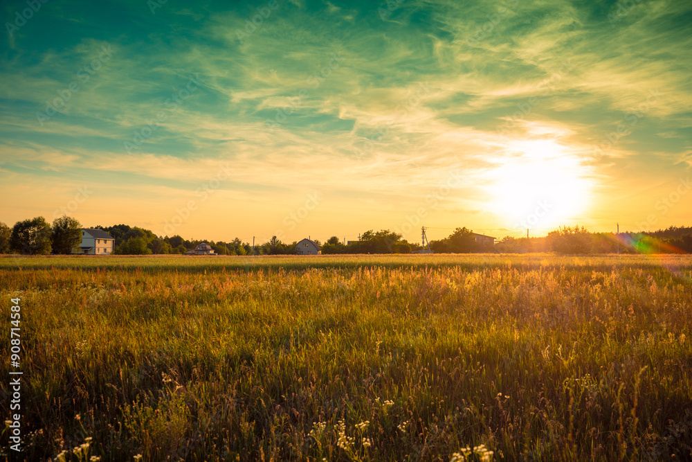Rural landscape with beautiful gradient evening sky at sunset. Green field and village on the horizon