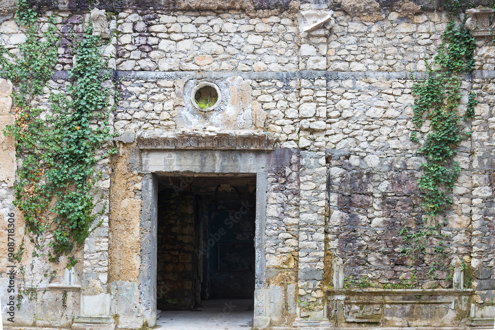 Empty doorway in the stone wall of a building. The stone wall of the house is covered with green ivy. Background with copy space Empty doorway in the stone wall of a building. The stone wall of the house is covered with green ivy. Background with copy space