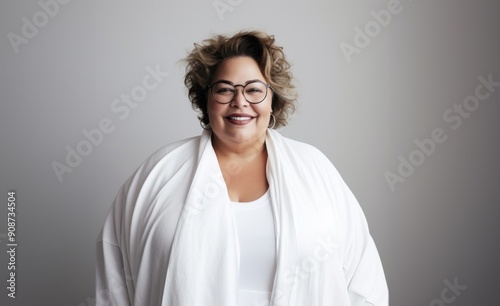 On a grey backdrop, a plump elderly blonde exudes confidence and charm, embracing her full-figured, matured grace