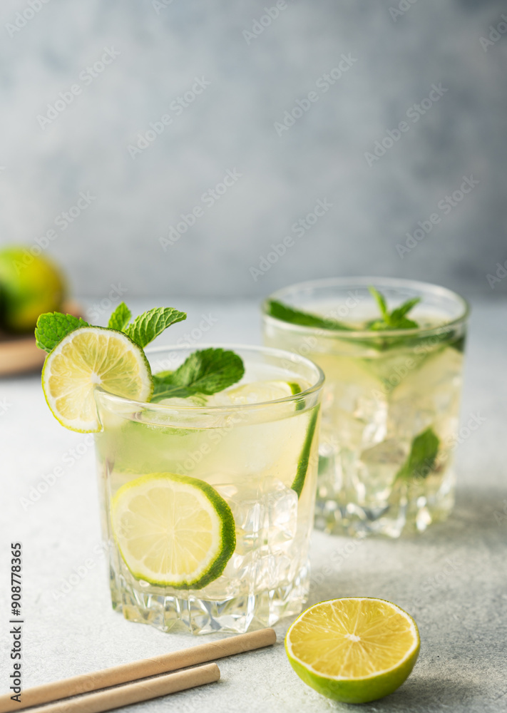 Two glasses mojito cocktail with fresh lime and paper tube on a texture background. Two glasses mojito cocktail with fresh lime and paper tube on a texture background.