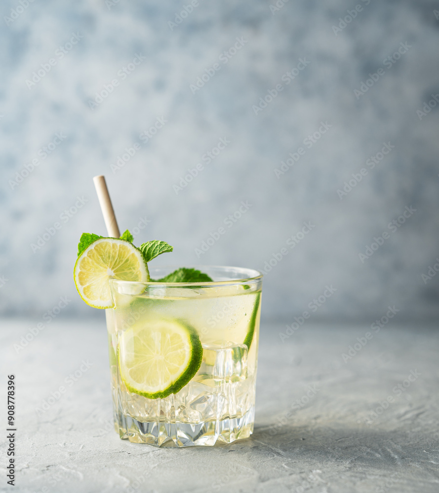 Mojito drink with fresh lime on a texture blue background. Refreshing cocktail with citrus fruits, mint and ice.