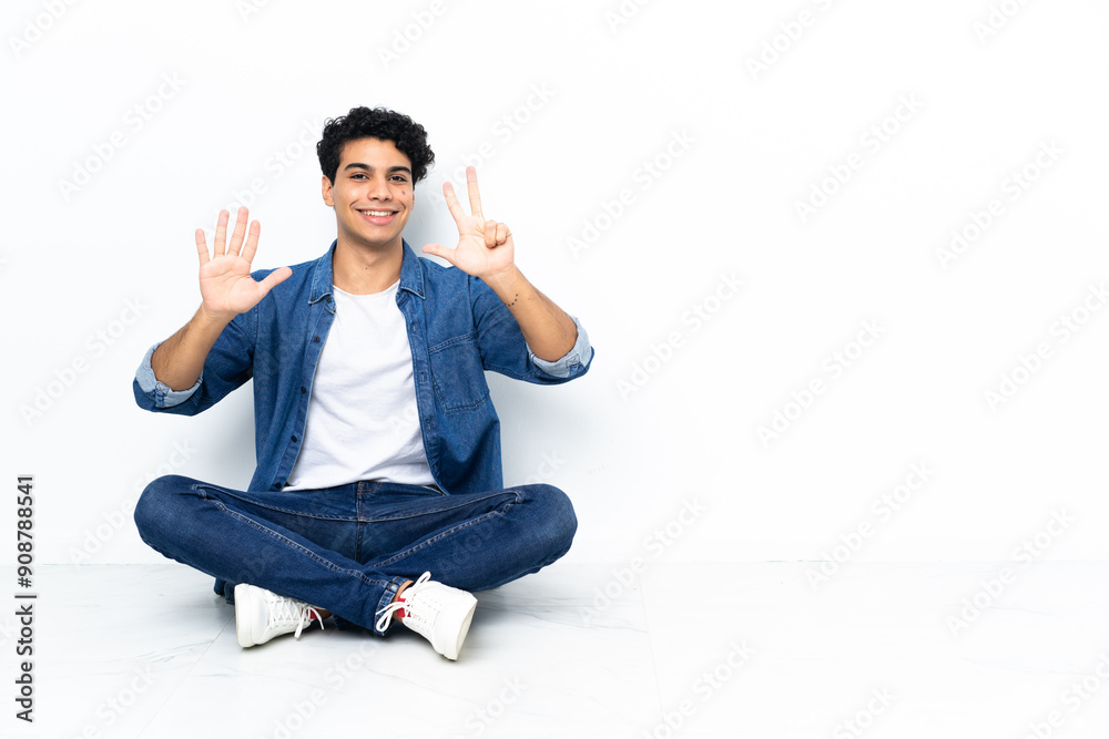 Venezuelan man sitting on the floor counting eight with fingers Venezuelan man sitting on the floor counting eight with fingers