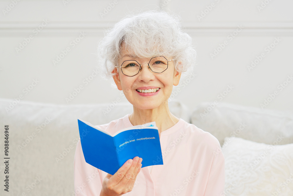 笑顔でお薬手帳を持つシニア女性　カメラ目線